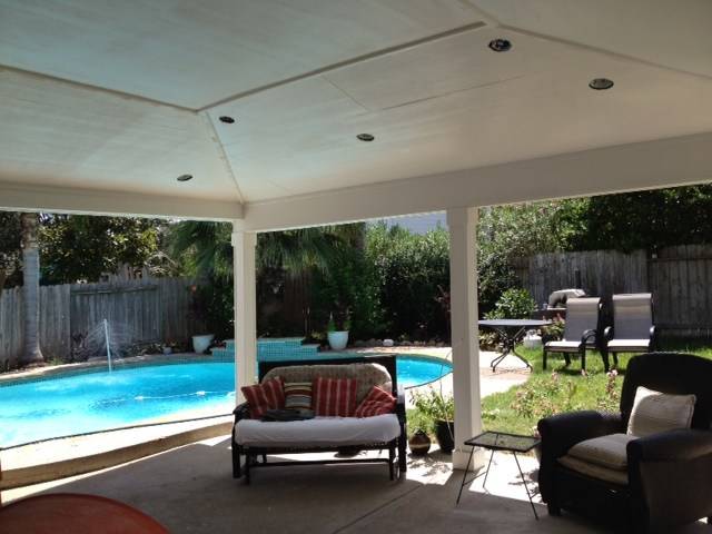 Covered patio with lounge chairs overlooking a backyard pool