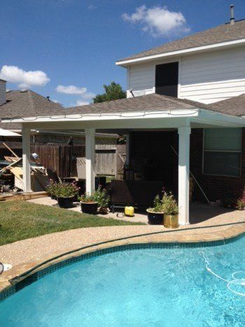 Backyard pool beside a house with a covered patio and potted plants