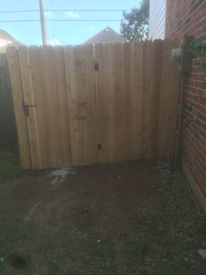 Wooden gate between brick walls in a small outdoor yard.
