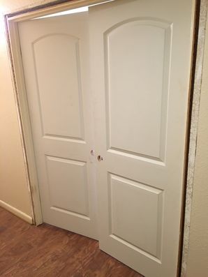 White double closet doors in a beige room with wood flooring