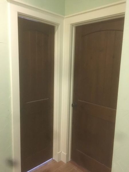 Two closed dark wood doors in a hallway with cream walls and trim.