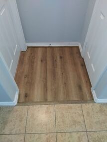 Narrow doorway with wood flooring transition between tiled floor and a small carpeted alcove.
