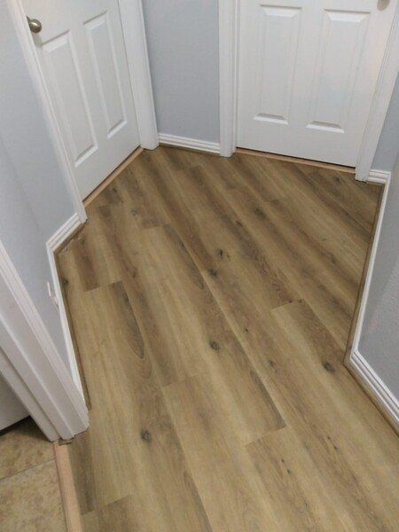 Light wood flooring in a small hallway with white doors and walls.