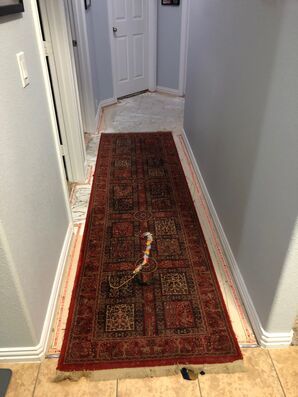 Narrow hallway with a red patterned runner rug leading to a closed white door.