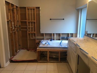 Unfinished bathroom with exposed wall framing, a built-in tub, and vanity under construction.