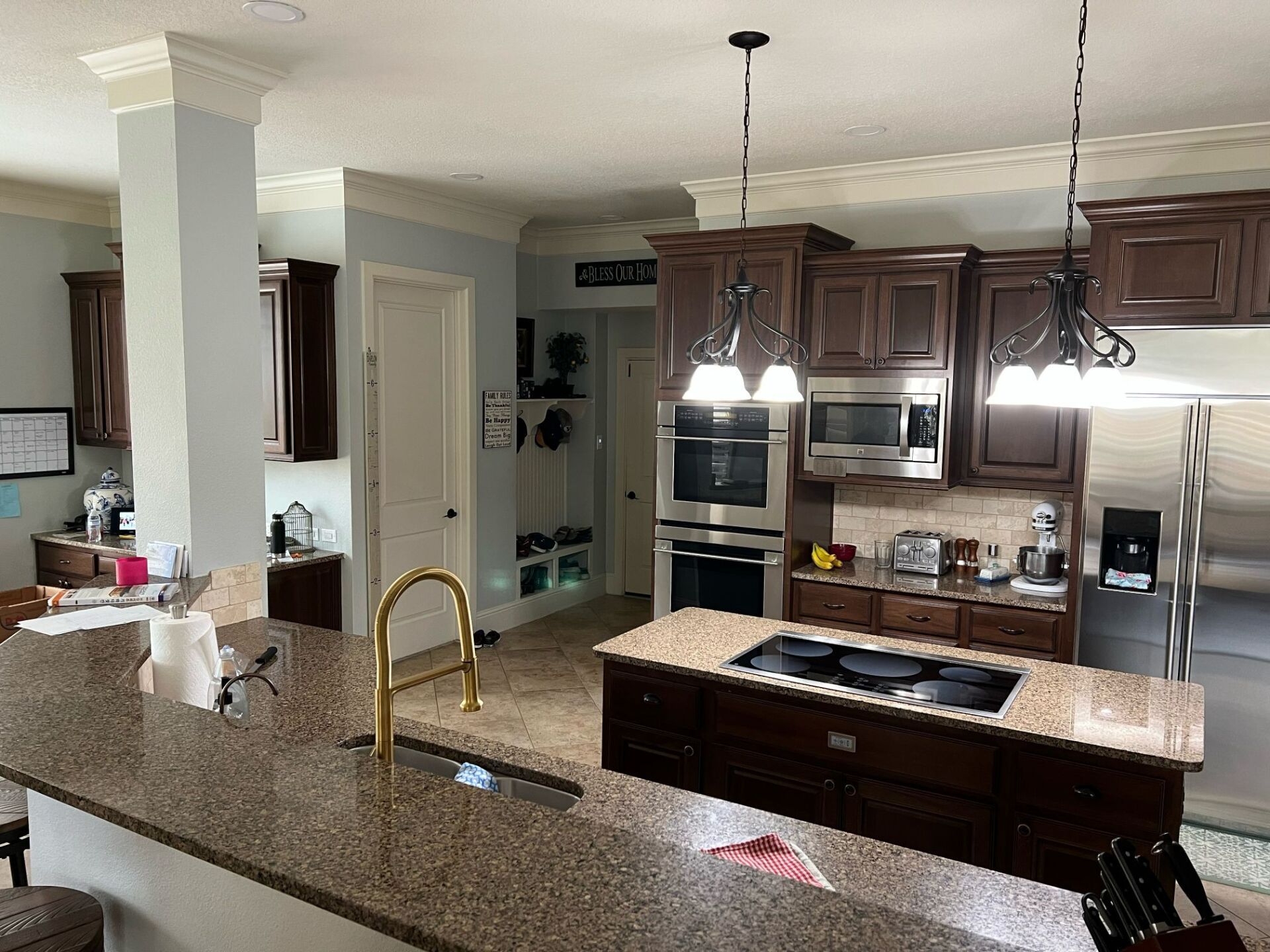Modern kitchen with granite island, pendant lights, stainless appliances, and dark wood cabinets