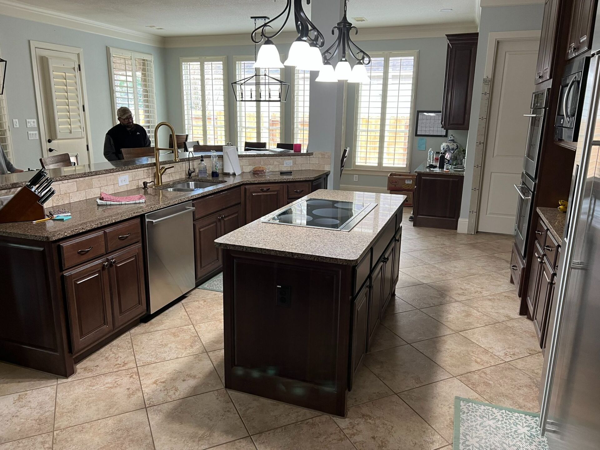 Spacious modern kitchen with a large island, dark wood cabinets, and bright windows at the back.