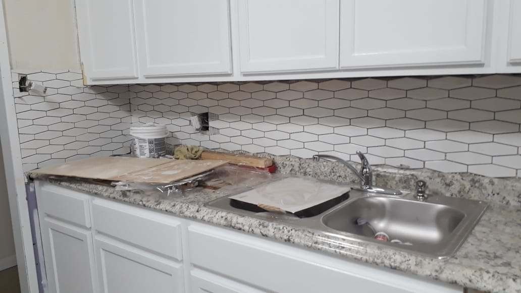 Kitchen countertop with sink, white cabinets, and unfinished backsplash installation