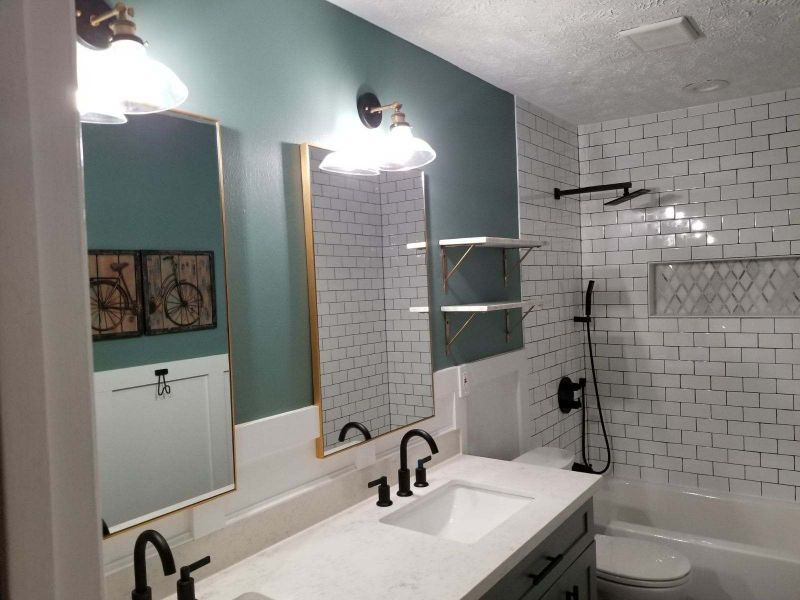 Modern bathroom with double sink vanity, mirrors, and white subway-tile shower.