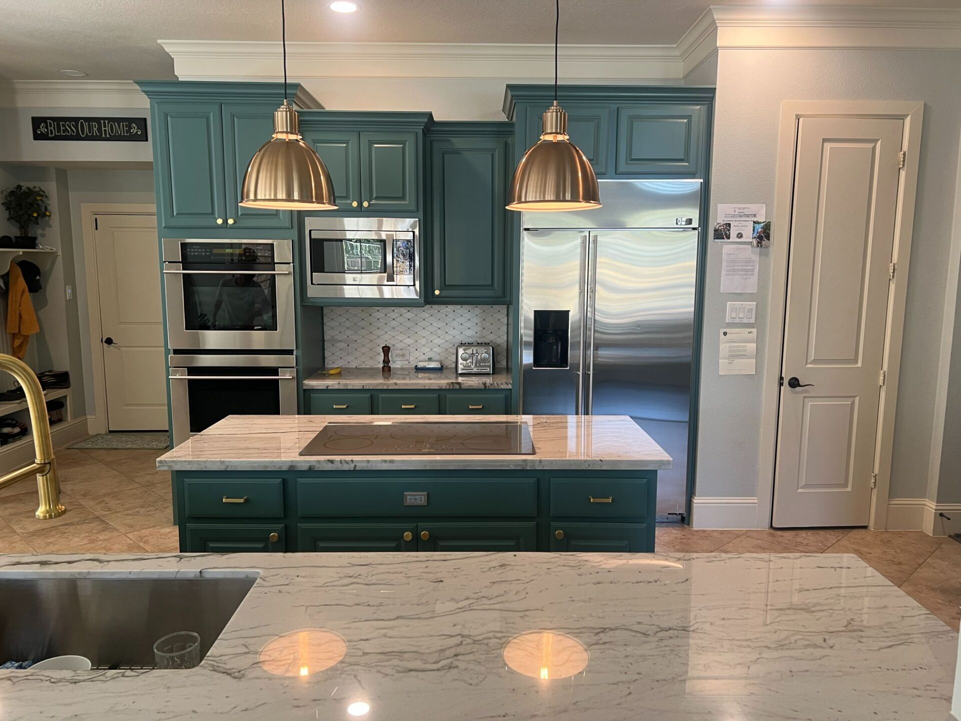 Modern kitchen with blue cabinets, stainless appliances, island, pendant lights, and white marble countertops