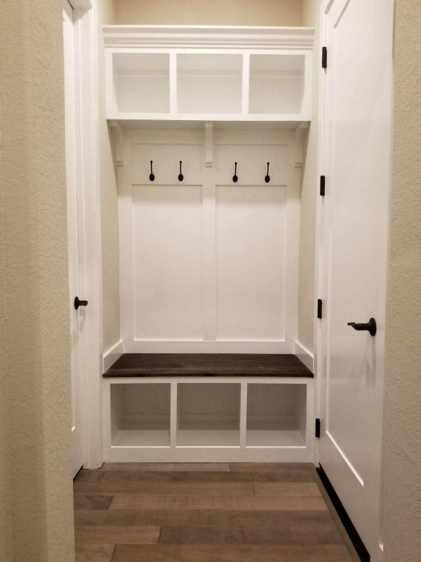 White hallway mudroom bench with cubbies, hooks, and upper cabinets on wood floor