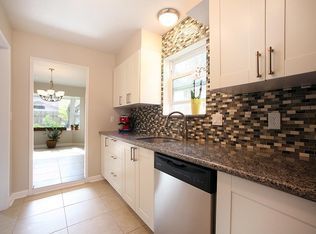 Bright modern kitchen with white cabinets, mosaic backsplash, granite counters, and a stainless-steel dishwasher.