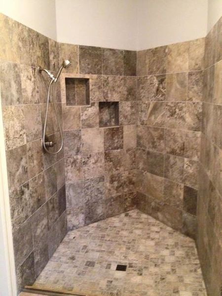 Tiled walk-in shower with built-in niches and a handheld showerhead.