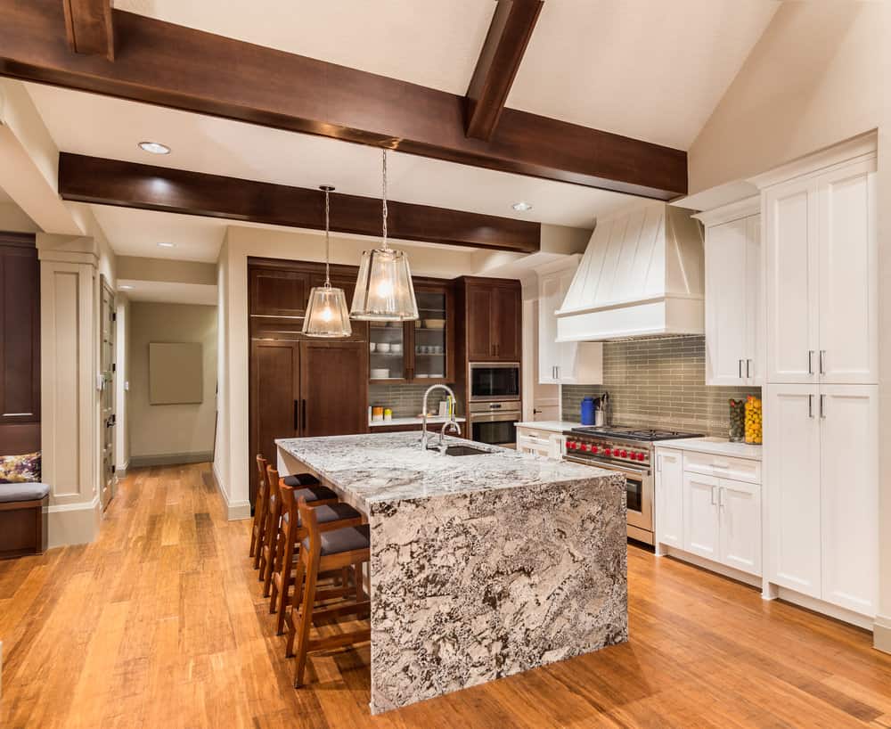 Modern kitchen with white cabinets, wood beams, and a granite island under pendant lights