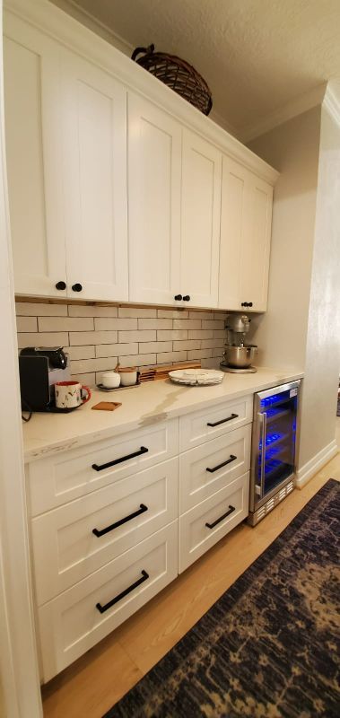 White kitchen cabinetry with countertop appliances and a built-in undercounter wine cooler