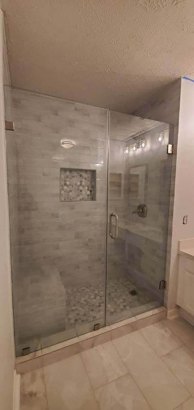 Modern tiled bathroom with a glass-enclosed walk-in shower and beige floor tiles