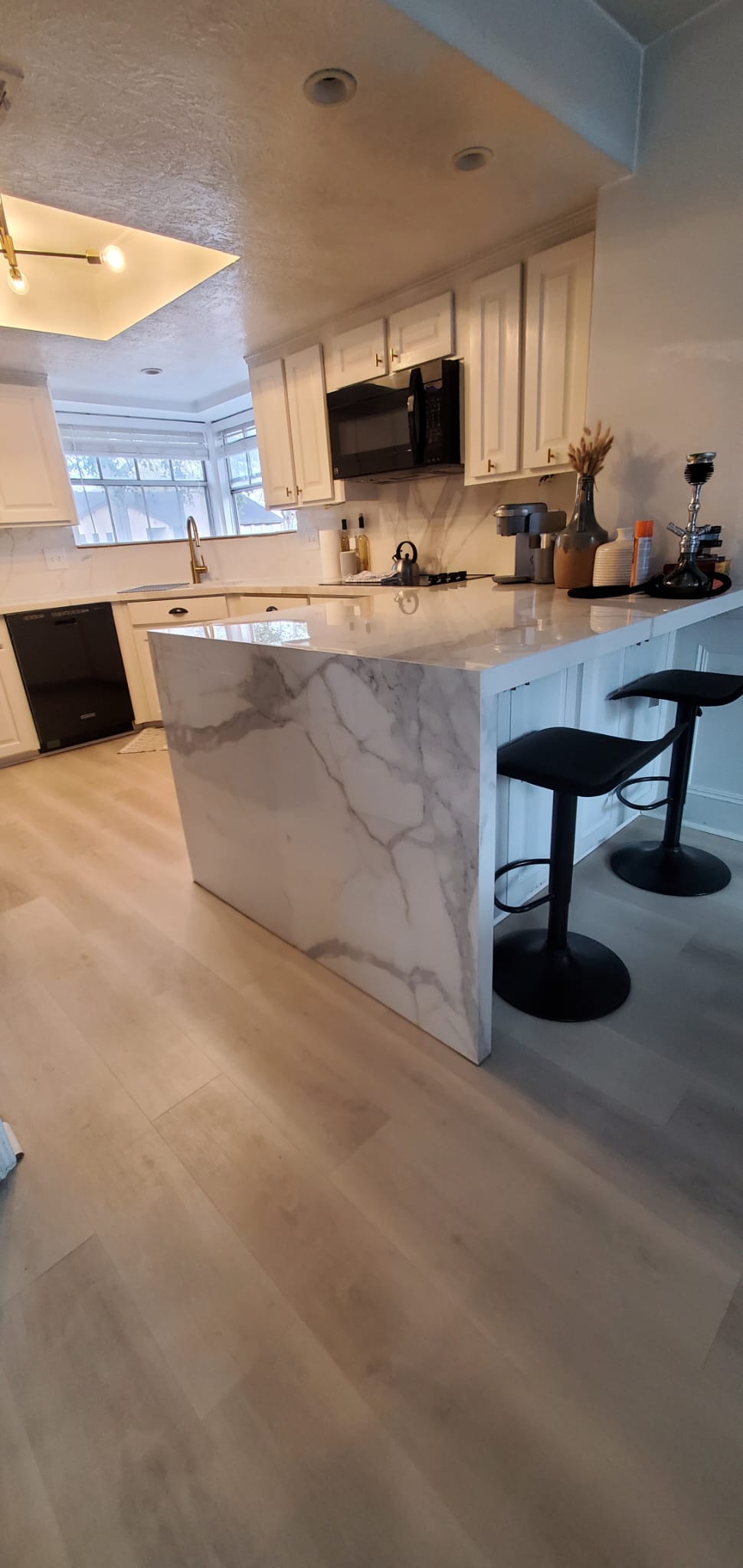Modern kitchen with marble island, pendant lights, and bar stools in a bright open-plan apartment