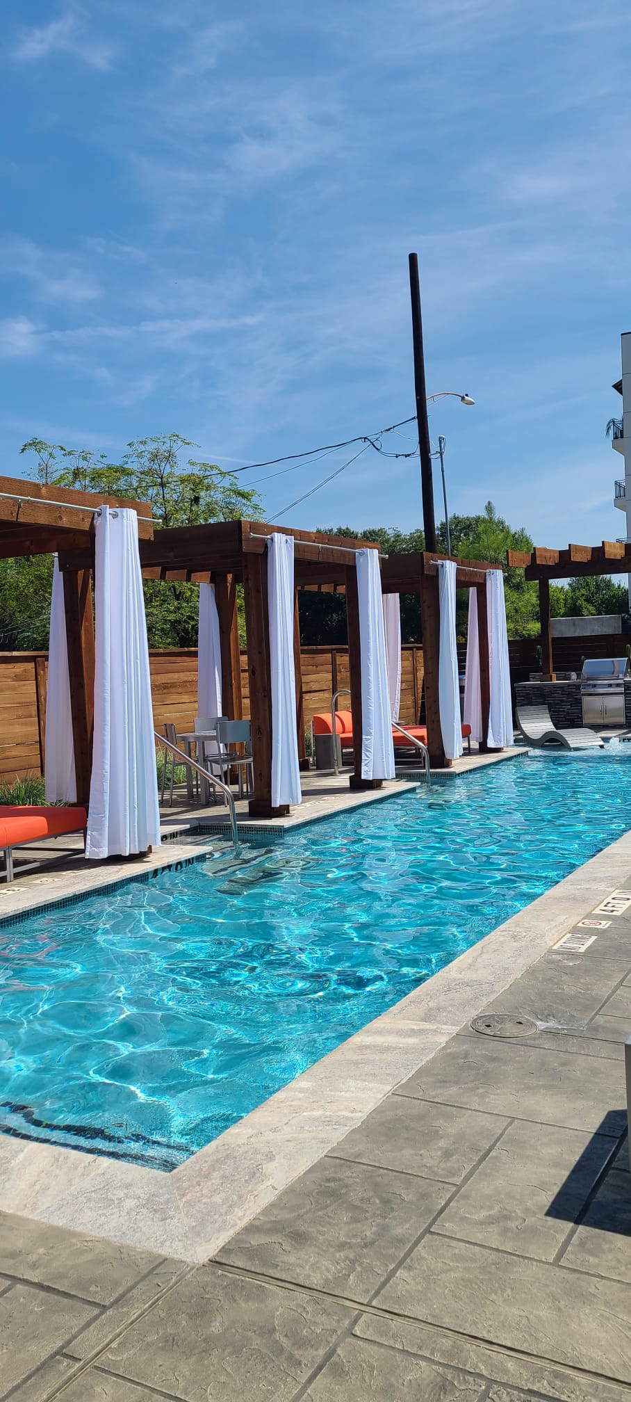 Outdoor pool with blue water, white cabanas, and a sunny sky