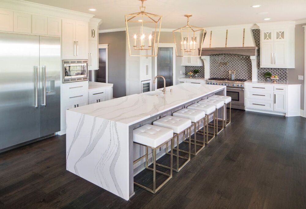 Bright modern kitchen with white cabinets, marble island, stainless steel fridge, and bar stools