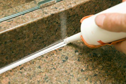 Caulk tube sealing a gap in a granite countertop with white sealant