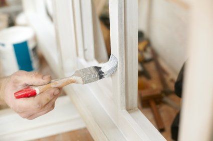 Hand painting a white window frame with a brush