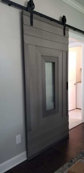 Gray sliding barn-style door with a narrow frosted glass panel in a home hallway.