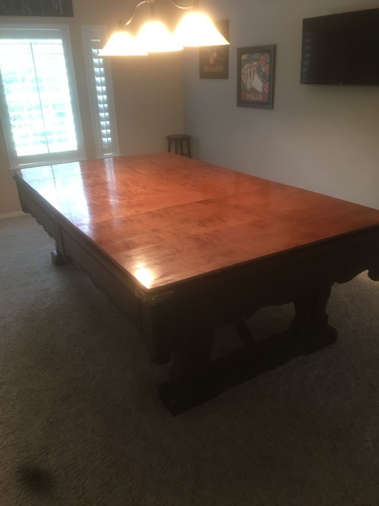 Large wooden dining table under a chandelier in a carpeted dining room