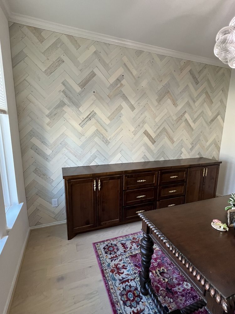 Empty dining room with patterned wallpaper, dark wood sideboard, and a table in the foreground.