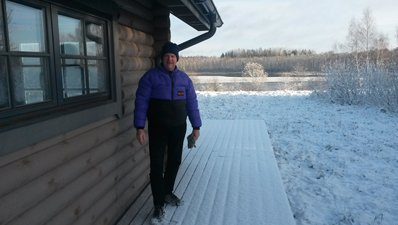 Person standing on a snowy deck beside a cabin in winter