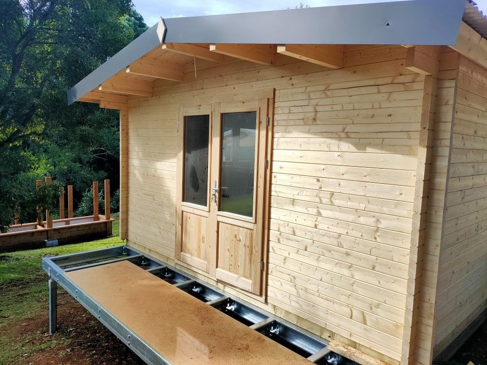 Small wooden cabin with a metal roof and front porch on a sunny day.
