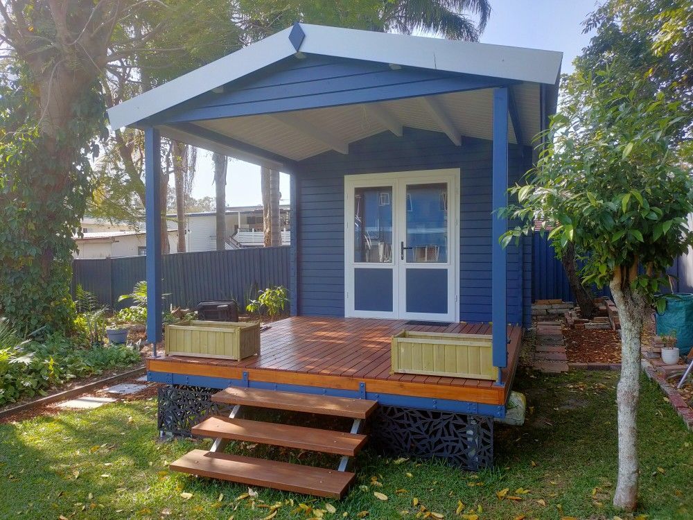 Small wooden shed under construction with porch steps in a fenced backyard.