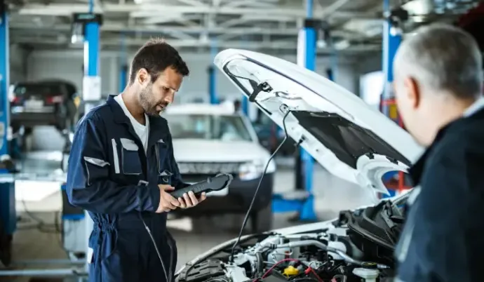 Dois mecânicos estão trabalhando em um carro em uma garagem Chevrolet.