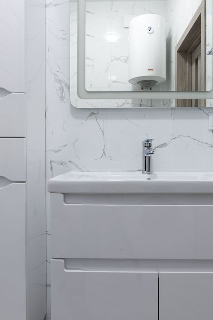 White bathroom sink with mirror and tiled wall