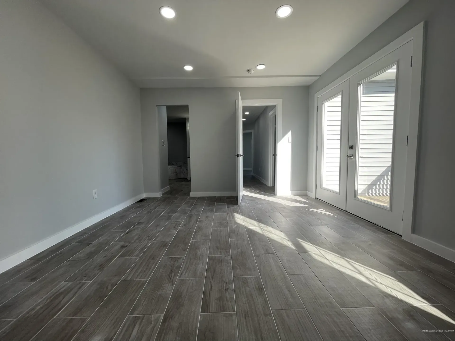 A large empty room with a wooden floor and sliding glass doors.