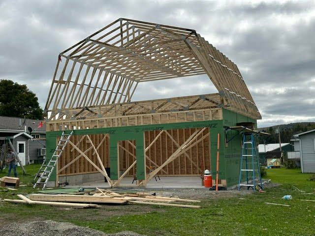 A large wooden structure is being built in a grassy field.