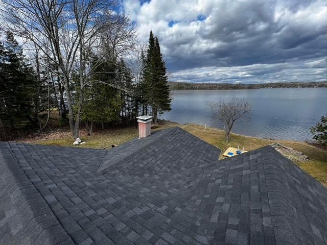 A roof with a view of a lake and trees.