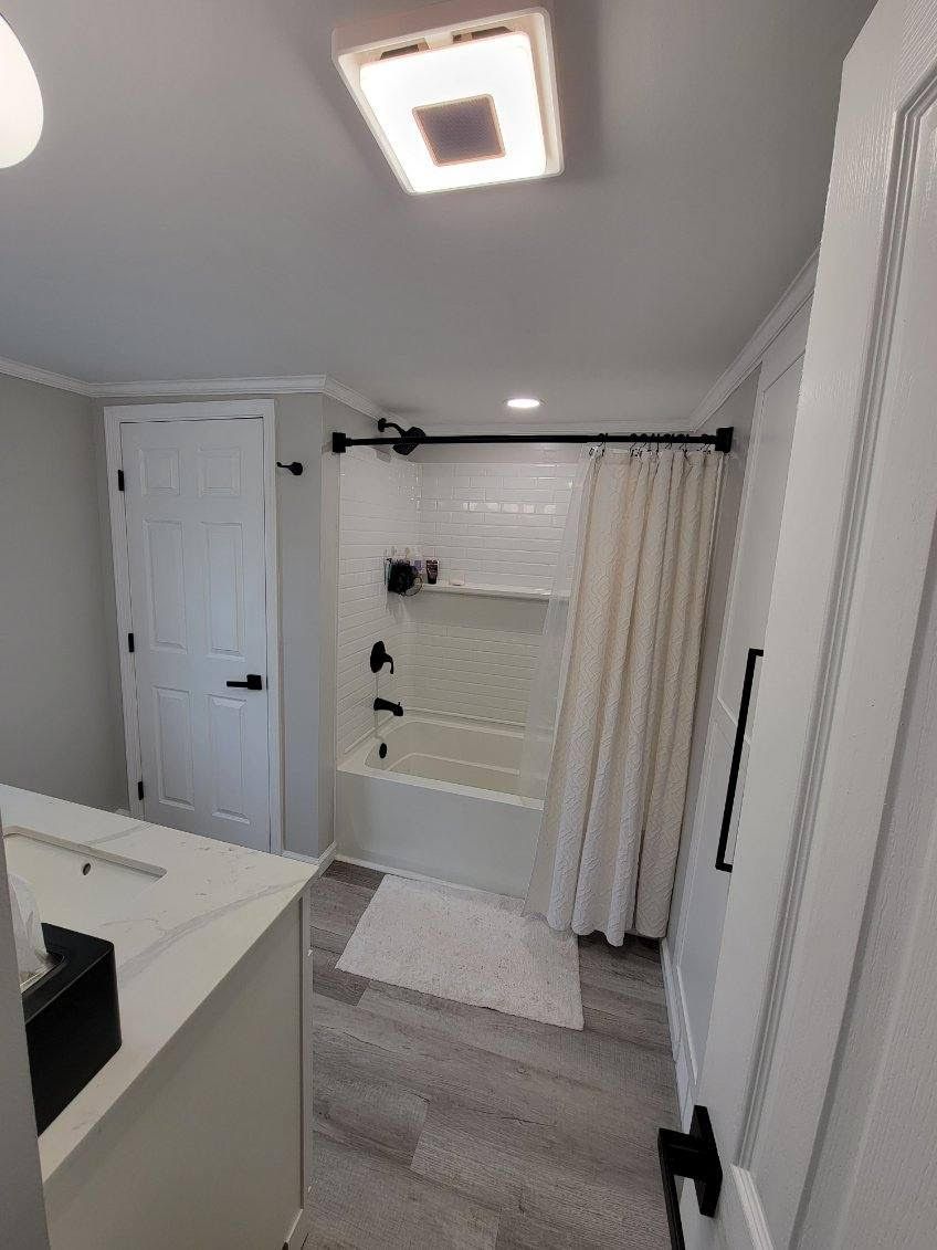 Bathroom with white walls, shower, and gray flooring.