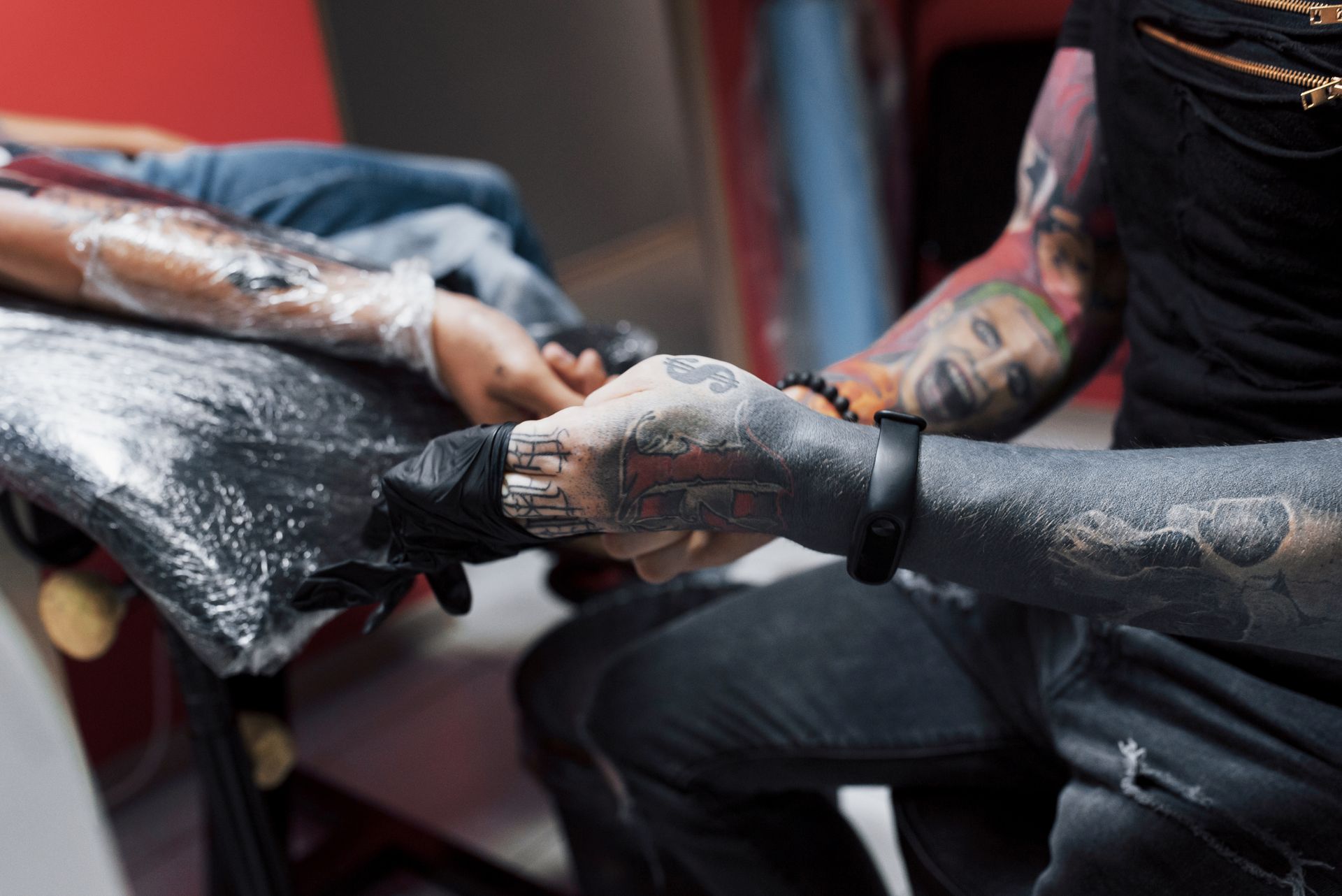 A man is getting a tattoo on a woman 's arm.