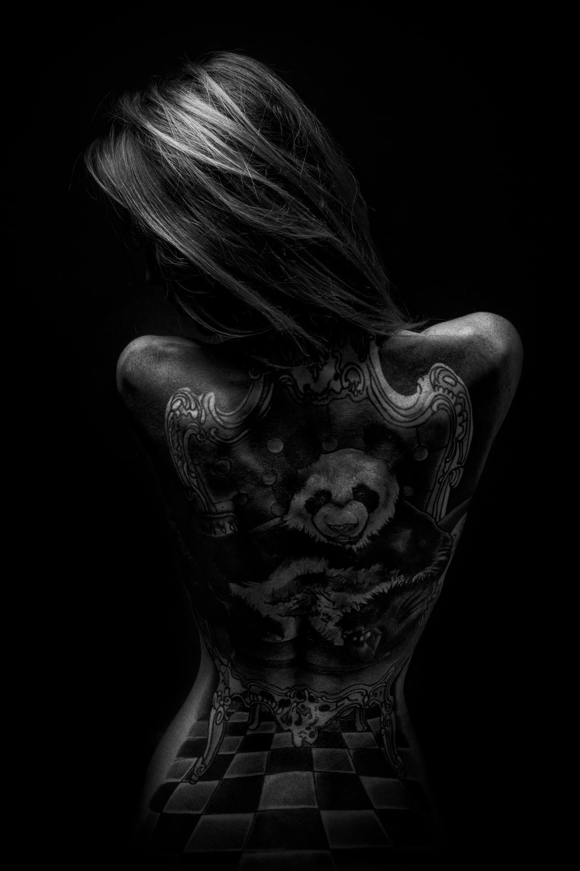 A black and white photo of a woman with tattoos on her back.