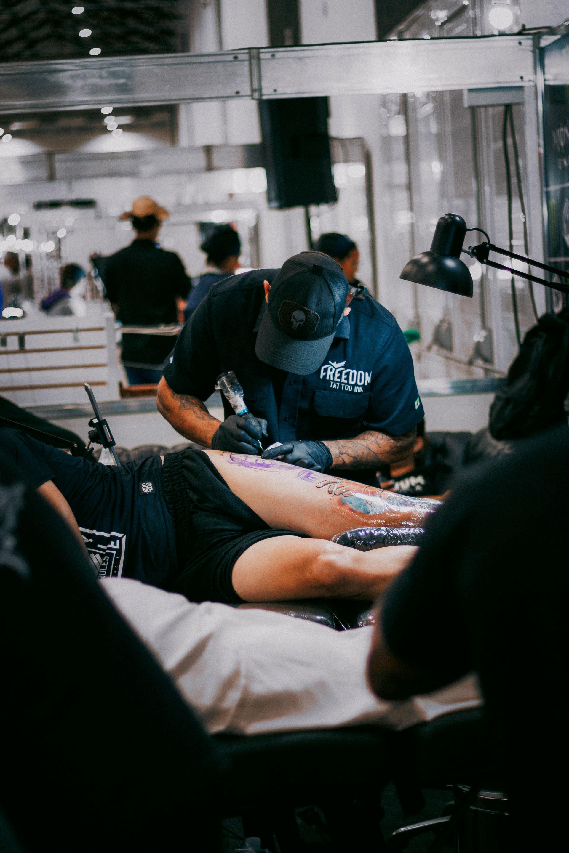 A man is getting a tattoo on a woman 's leg.