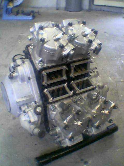 Large silver engine or compressor unit on a workshop floor, shown in close-up.