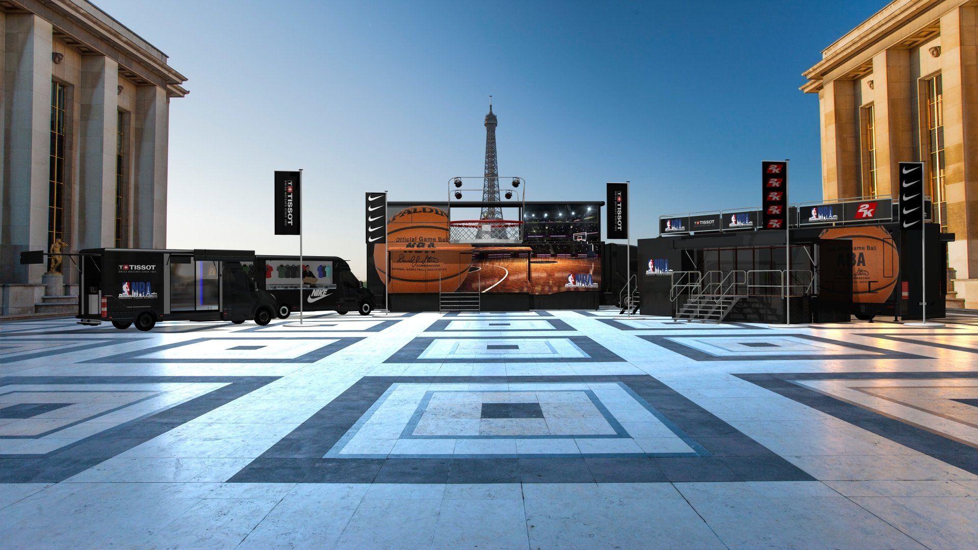 Outdoor basketball court with a central stage and banners between two stone buildings under a clear blue sky
