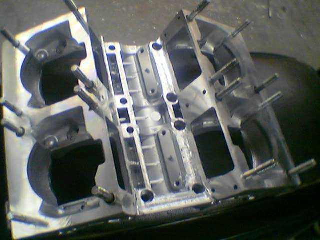 Car engine block with pistons and metal components on a workbench