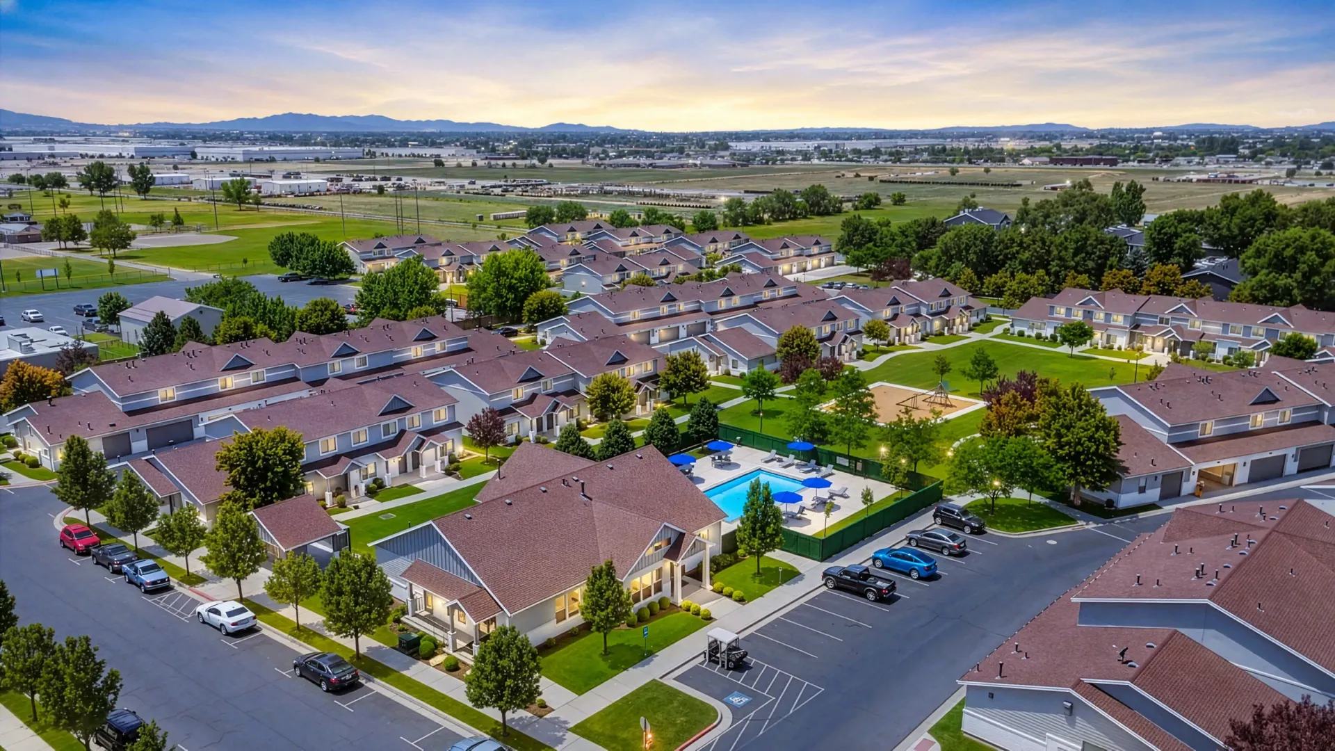 Aerial view of an apartment complex featuring a swimming pool, playground, and surrounding buildings at Mountain View Townhomes, offering townhomes in Ogden, UT.