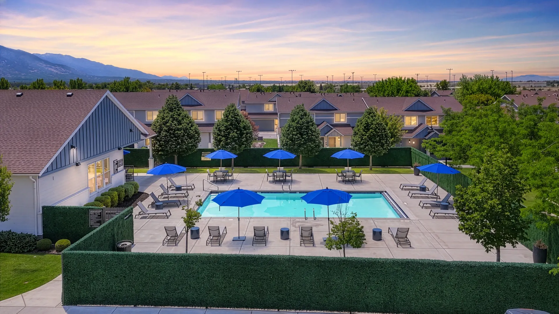 Outdoor swimming pool with lounge chairs and umbrellas at Mountain View Townhomes, offering townhomes in Ogden, UT.