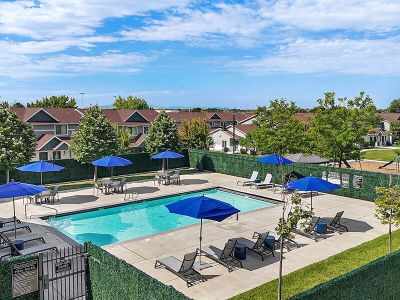 Mountain View Townhomes community pool area with blue umbrellas and lounge chairs.