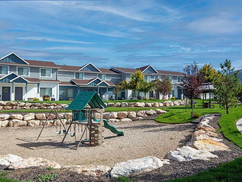 Mountain View Townhomes Playground with swings and a slide in a landscaped apartment community.