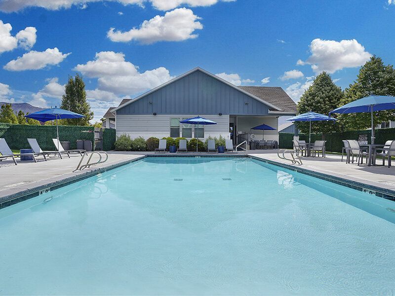 Mountain View Townhomes pool area at a multifamily community with lounge chairs and blue umbrellas.