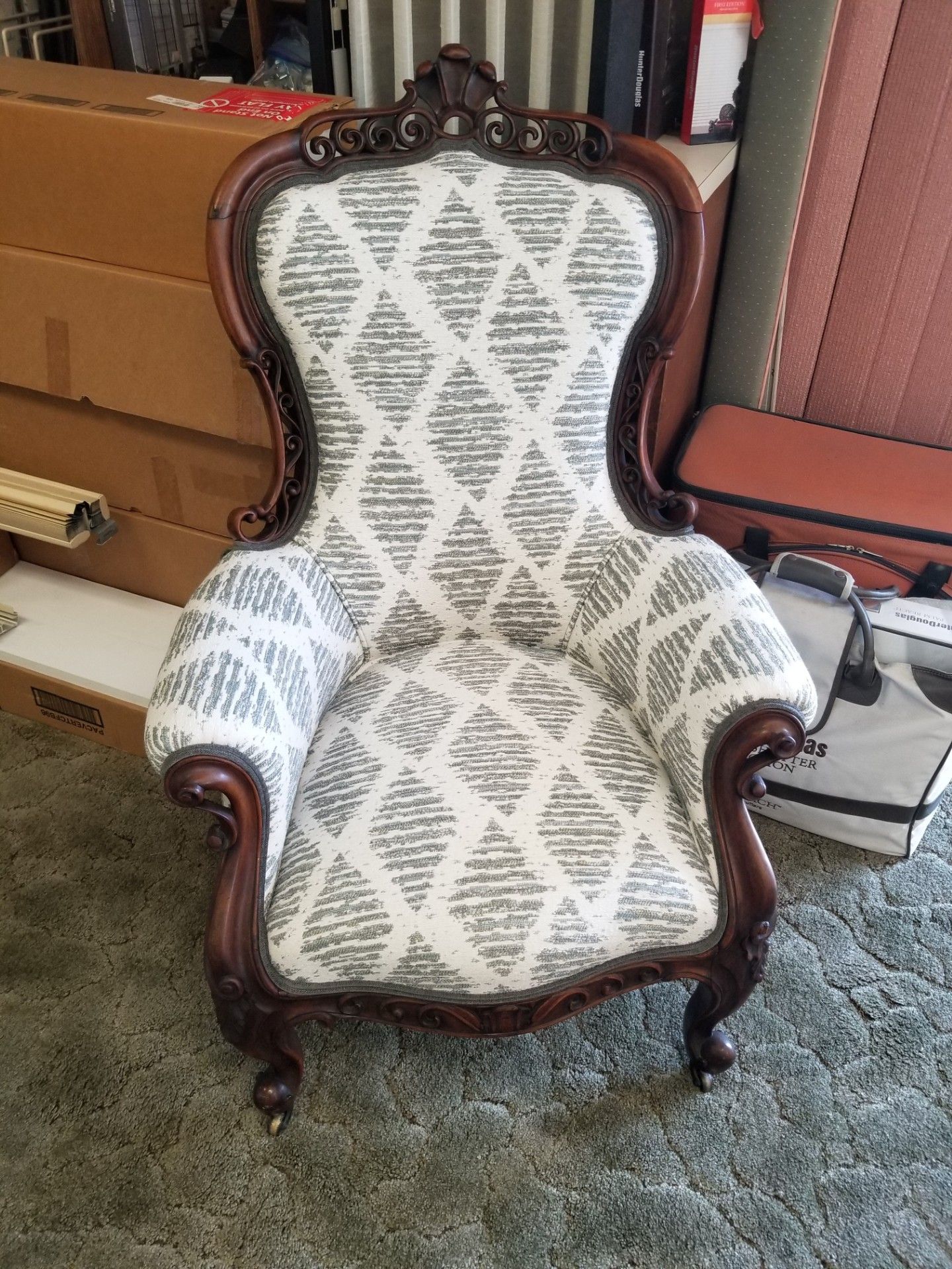 Ornate armchair with patterned gray and white fabric, dark wood frame, and carved details.