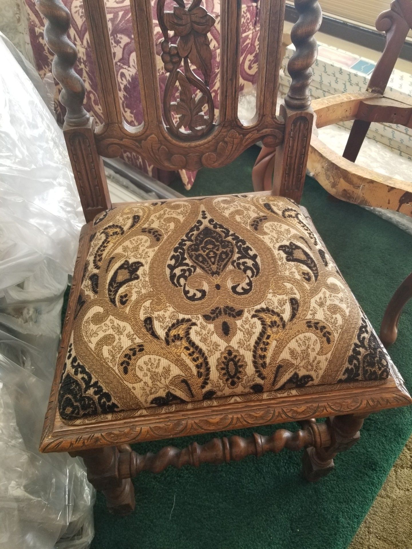 Ornate wooden chair with carved back and paisley patterned seat.